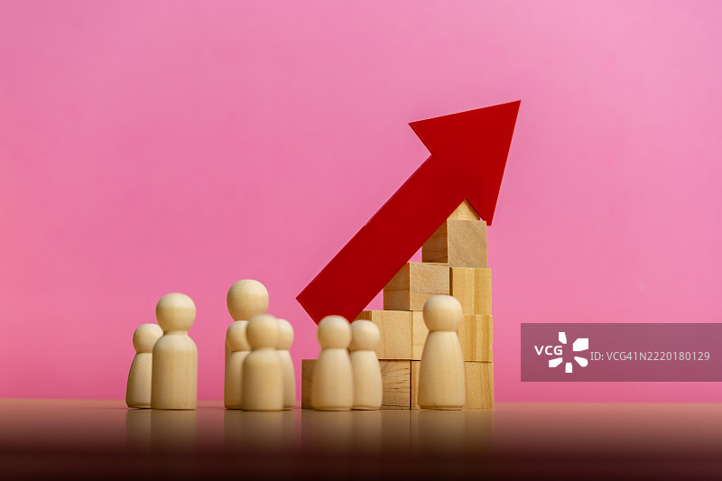 木制人偶看着一个由木块支撑的向上指的红色箭头图片素材