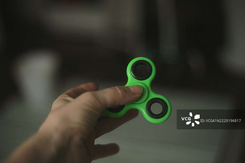 抗压放松的小玩具，适合疲惫的人。男孩在玩指尖陀螺。图片素材