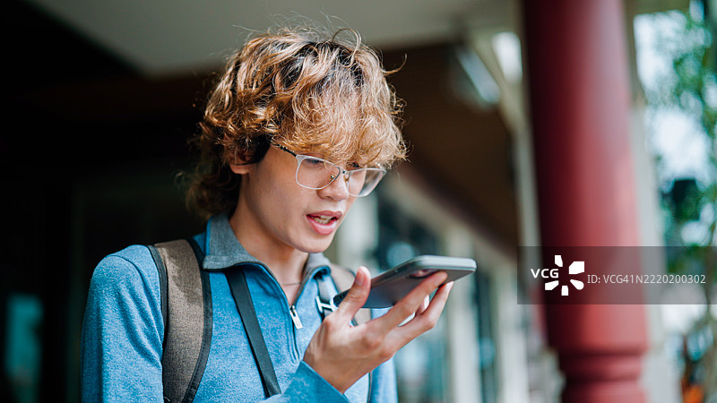 年轻的亚洲男子在泰国旅行时使用人工智能将他的语言翻译成泰语。图片素材