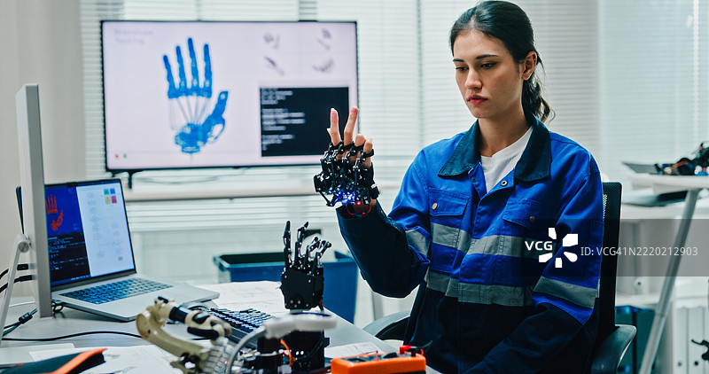 年轻女性工程师在科技实验室操作机器人手臂，进行人工智能和机器学习的开发。人工智能与机器人技术开发。图片素材