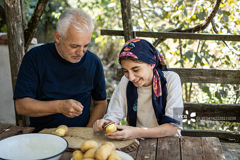 可爱的女孩和她的爸爸一起剥土豆图片素材
