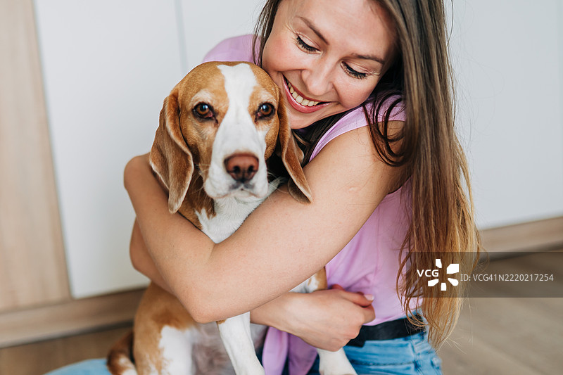 女人在温暖而充满爱的场景中拥抱一只比格犬图片素材
