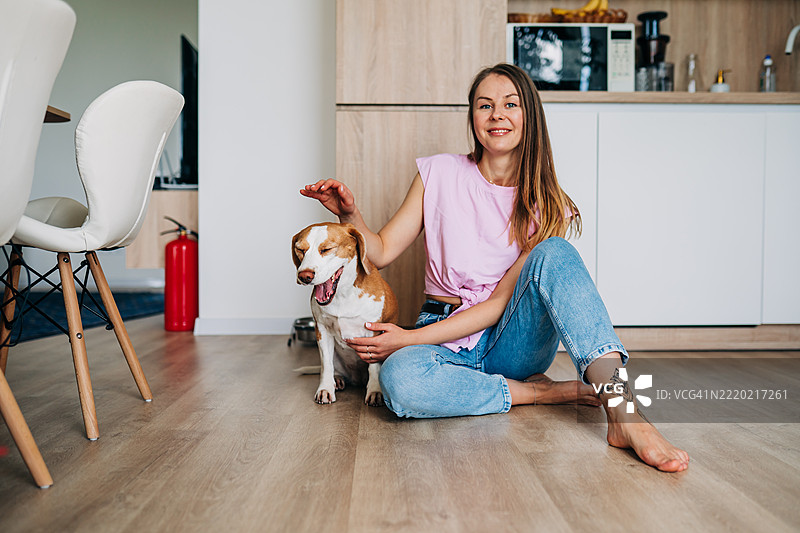 女人在温暖而充满爱的场景中拥抱一只比格犬图片素材