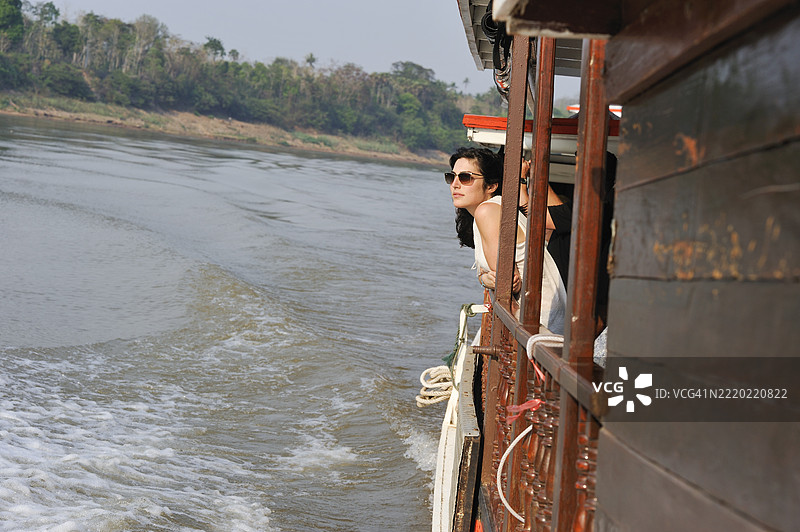 年轻女性站在老挝乌多姆赛省湄公河上的Luang Say Lodge and Cruises游船的栏杆旁图片素材