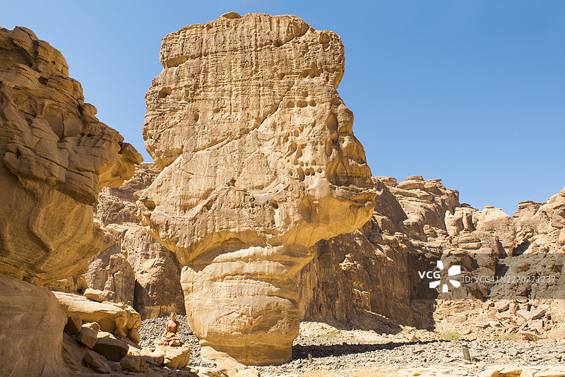 在沙特阿拉伯麦地那省阿沙尔谷的沙岩峡谷中，一位女性正在练习瑜伽姿势。图片素材