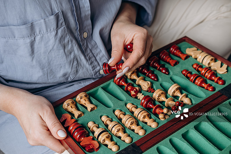 一名玩家在经典棋盘上用木制棋子进行战略性移动，展现出专注和战术思考，环境温馨舒适。图片素材