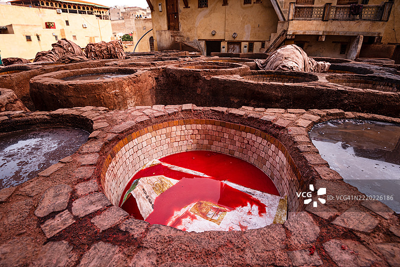 摩洛哥非斯的联合国教科文组织传统皮革鞣制坑中的鲜艳红色染料图片素材