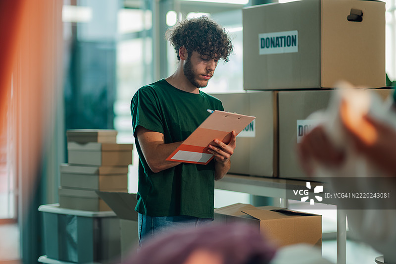 年轻男性志愿者在纸箱中记录捐款情况图片素材