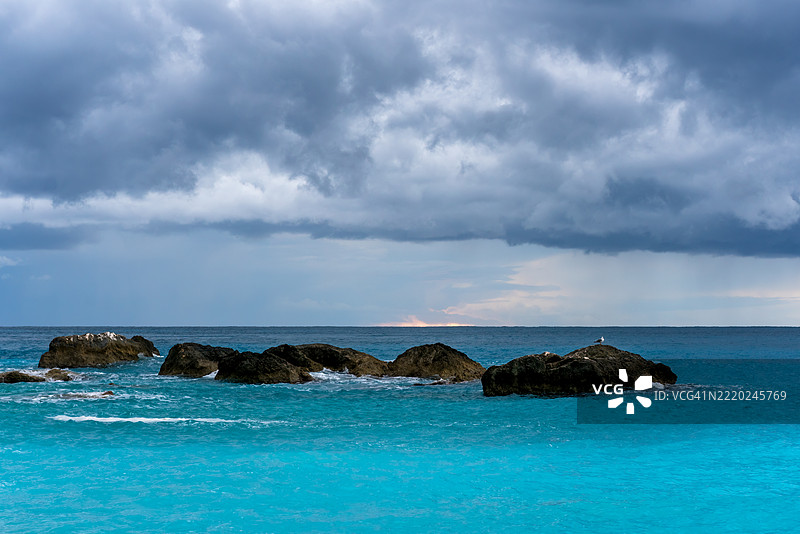 暴风雨天，希腊碧绿海面上岩石上的海鸥图片素材