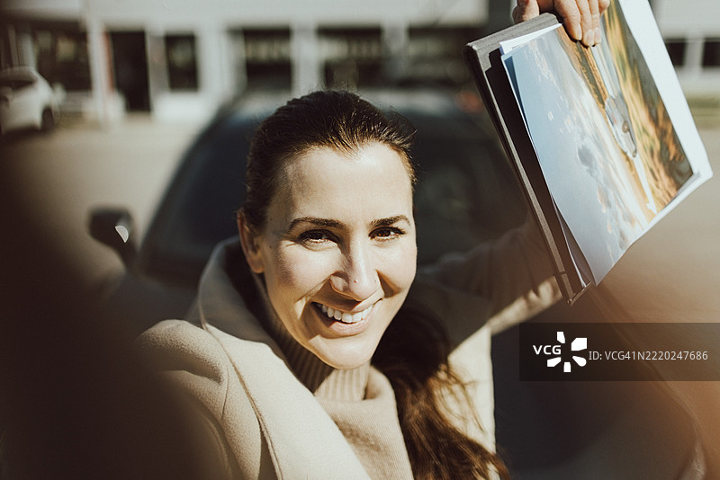 兴奋的女性手持宣传册与新车自拍图片素材