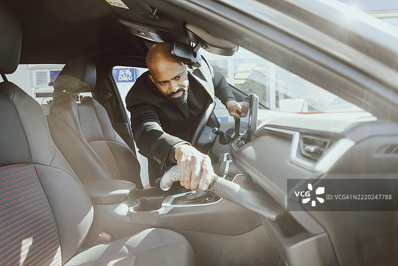 销售员在展厅为汽车的仪表盘吸尘图片素材