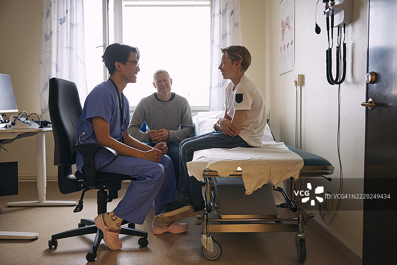 快乐的医生与坐在检查台上的男孩交谈图片素材