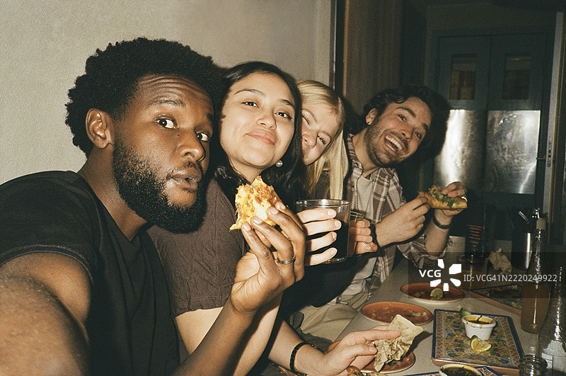 年轻男子在餐厅与朋友一起吃塔可时自拍的肖像图片素材