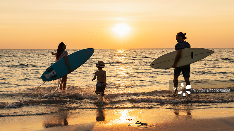一个快乐的家庭在海滩活动中享受他们的夏季假期，伴随着日落的美景，共同度过美好时光。图片素材