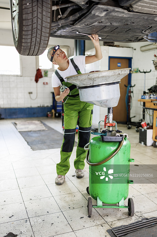 女性机械师使用抽油工具进行换油程序图片素材