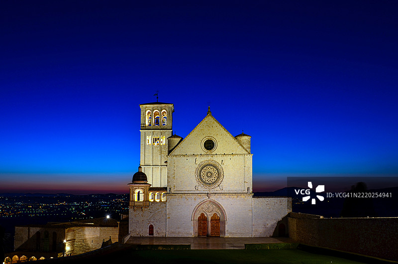 阿西西，翁布里亚，意大利的圣方济各大教堂在黄昏时分被美丽的日落色彩照亮。图片素材