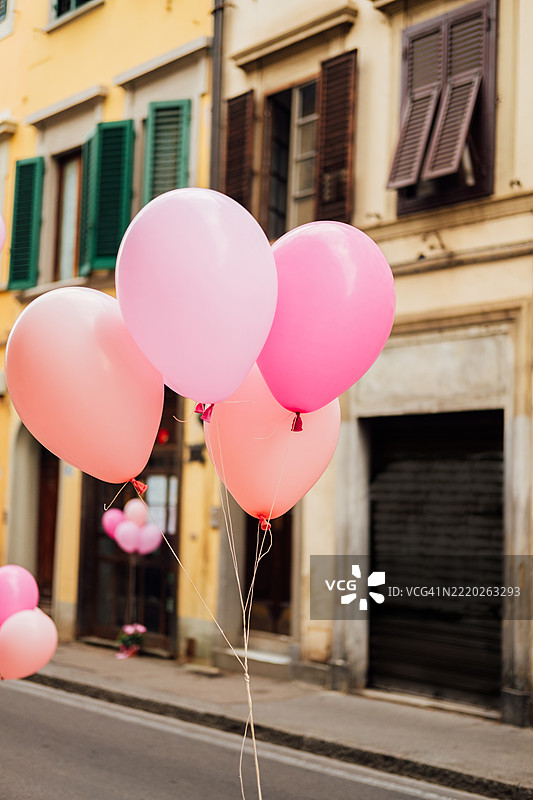 粉色和柔和色调的气球漂浮在古雅的欧洲住宅建筑附近图片素材