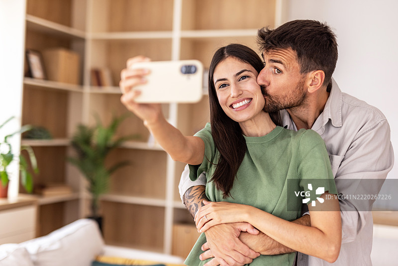 幸福的情侣在家中拥抱亲吻时自拍图片素材
