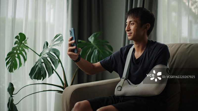 戴着手臂石膏的男子自拍。图片素材