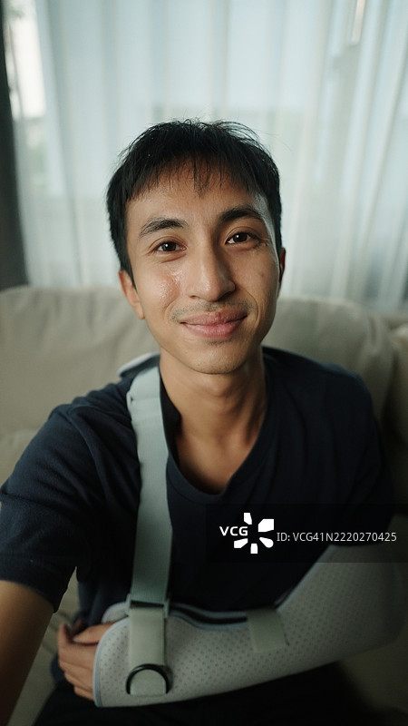 戴着手臂石膏的男子自拍。图片素材