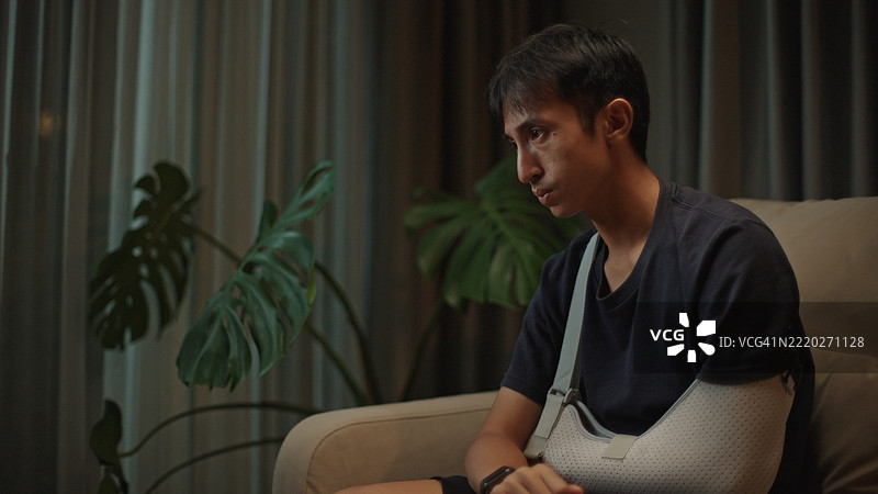 戴着手臂石膏的男人感到沮丧。图片素材