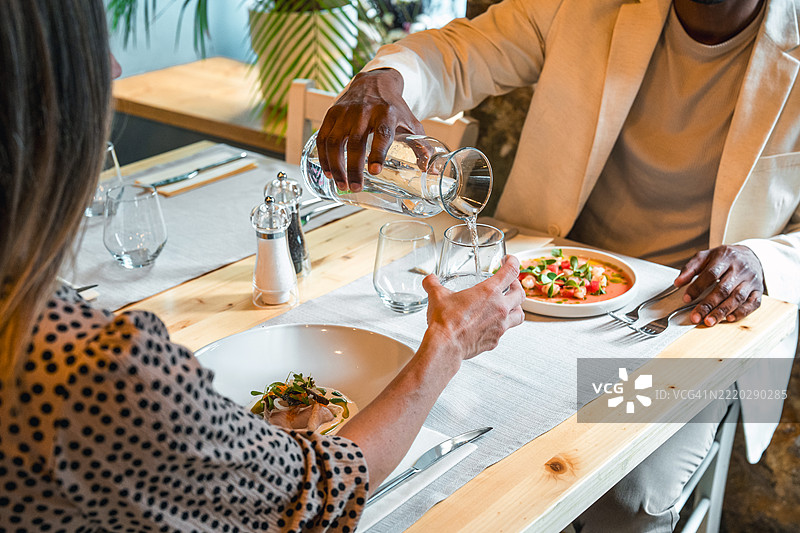 优雅的高档餐饮，明亮餐厅环境中新鲜菜肴与水的倒入图片素材