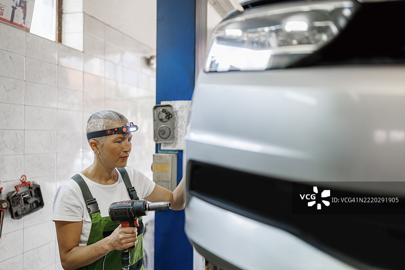 女性机械师使用气动扳手更换汽车轮胎图片素材