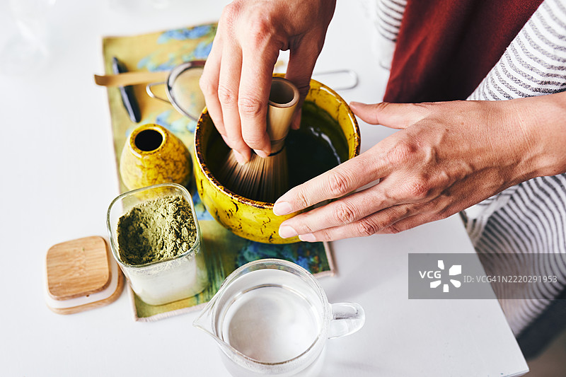 在时尚厨房中用传统竹 whisk 准备抹茶绿茶图片素材