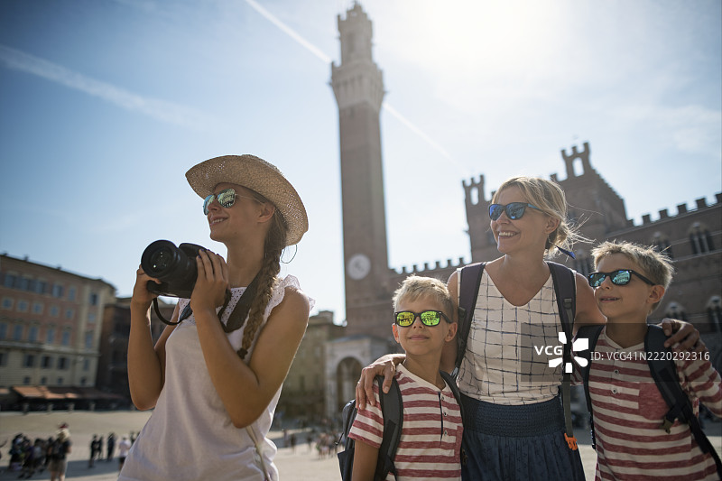 游客家庭在意大利锡耶纳的坎波广场探索，欣赏历史悠久的市政宫。图片素材