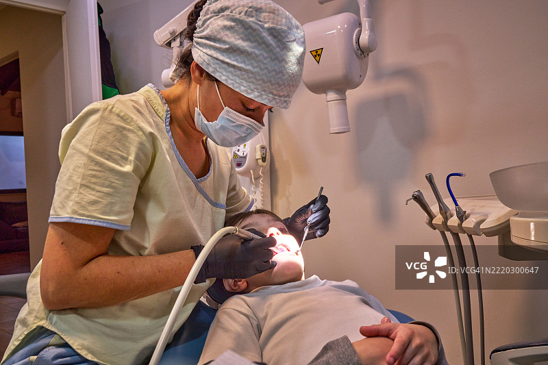 年轻女牙医正在为儿童患者修复牙齿蛀洞图片素材