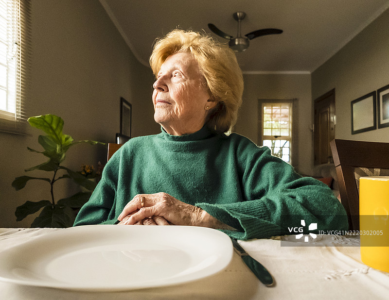安静的家中，老年女性在餐桌旁等待图片素材