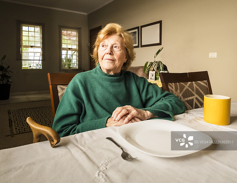 安静的家中，老年女性在餐桌旁等待图片素材