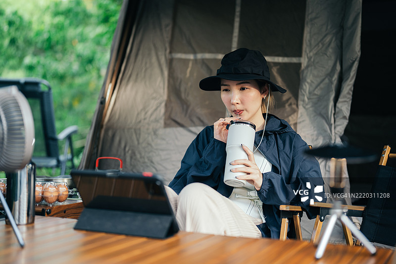 亚洲女性在露营地放松时使用平板电脑图片素材