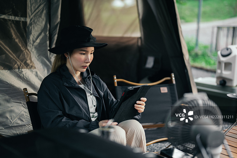 亚洲女性在露营地放松时使用平板电脑图片素材