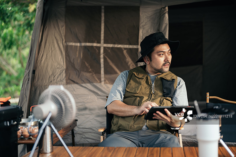 亚洲男子在露营地放松时使用平板电脑图片素材