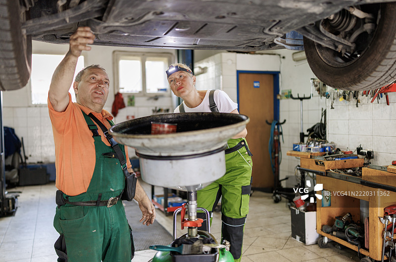 两名汽车维修工正在进行机油抽取图片素材