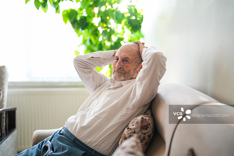 孤独的老年男子在家中沉思，手持拐杖。图片素材