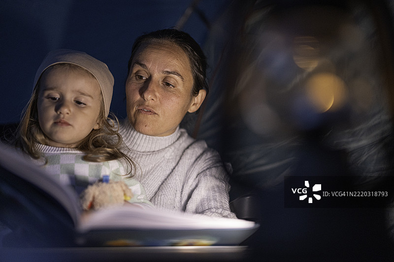 母亲在灯光下给女儿讲睡前故事图片素材