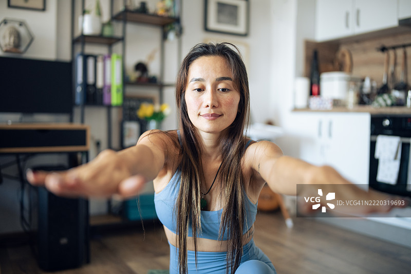注重身材的亚洲女性在家中进行拉伸和瑜伽练习。图片素材