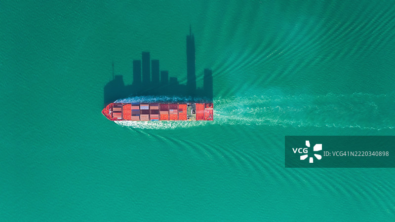 航拍视角的集装箱货船，满载集装箱，从商业港口的码头出发，适用于商业物流、进出口、运输或货运。图片素材