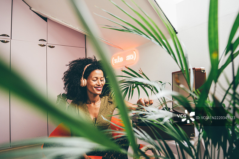 年轻女性在家中听唱片机。图片素材