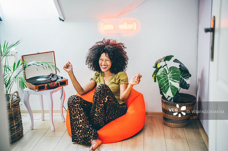 年轻女性在家中听着唱片机跳舞。图片素材