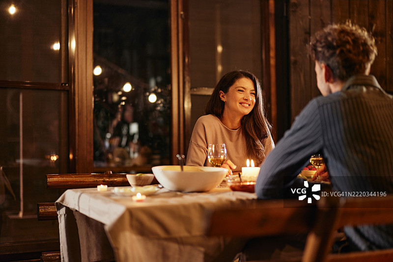 快乐的女人在露台上与丈夫共进晚餐时交谈。图片素材