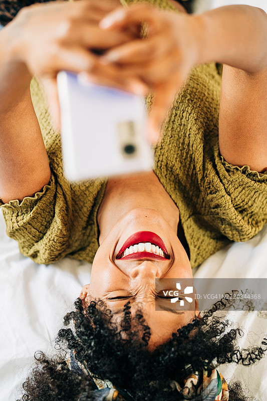 女人在家床上使用手机。图片素材