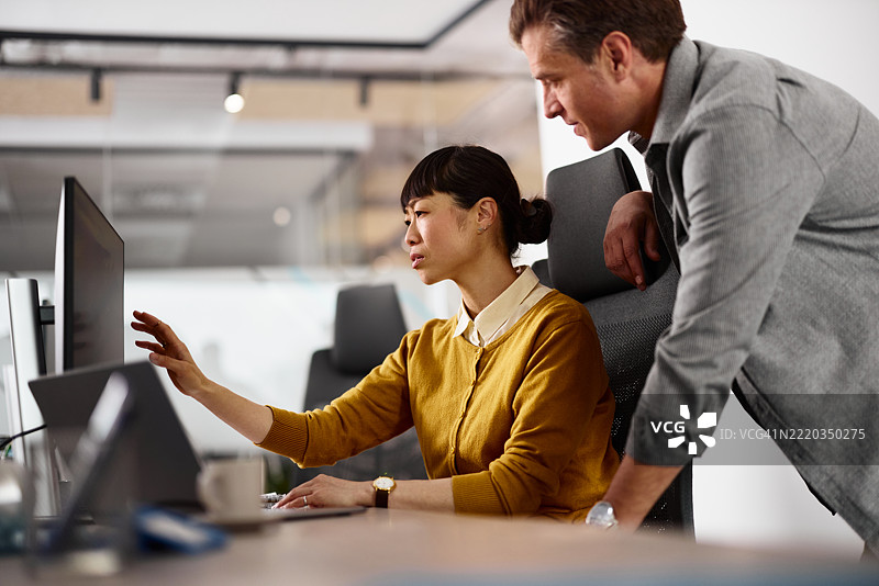 中年程序员在办公室使用电脑工作。图片素材