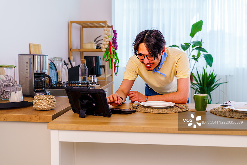 在家远程工作，视频通话，男性与笔记本电脑，互联网连接或会议通话。男性，企业家或演讲者在厨房进行对话或网络研讨会。图片素材