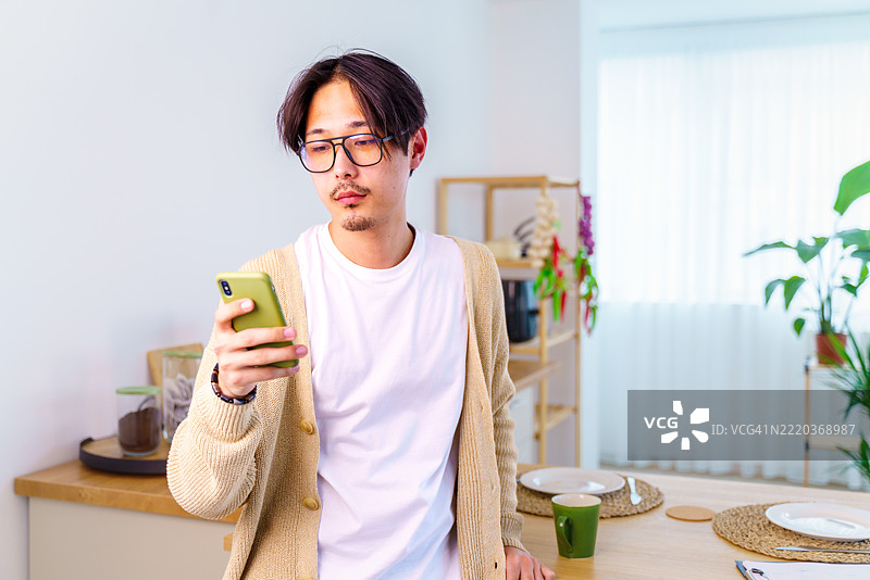 现代企业家，穿着优雅休闲服装的魅力男士，一边使用智能手机，一边手握咖啡杯。图片素材