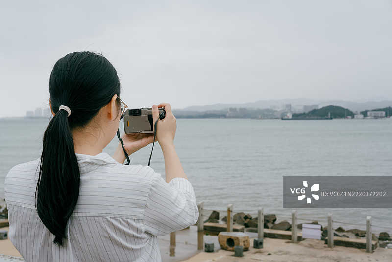 母亲和孩子在海滩用复古相机拍照；老式胶卷相机图片素材