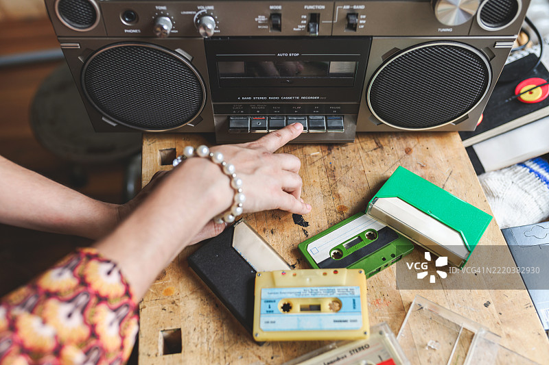 女性手按下复古磁带录音机的播放按钮图片素材