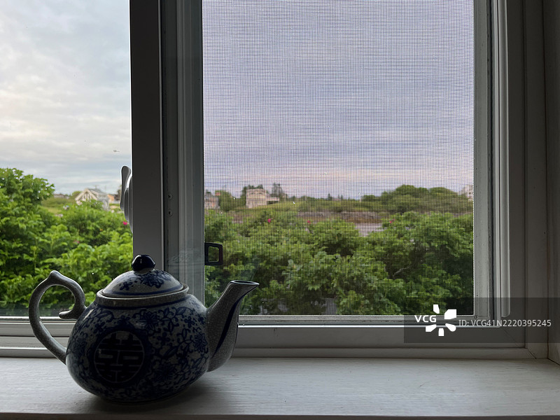 窗台上的茶壶。透过窗户看到缅因州海岸的小港口。图片素材